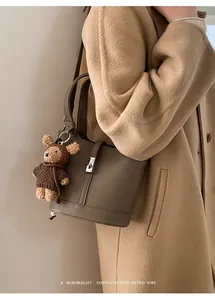 Borsa a secchiello marrone in pelle martellata con un ciondolo a orsetto sul manico