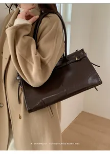 Détail du sac cabas marron foncé avec texture cuir brillant et boucle dorée en forme d'E