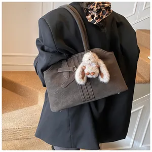 Détail d'un grand cabas en daim marron avec sangles décoratives et charm lapin en peluche