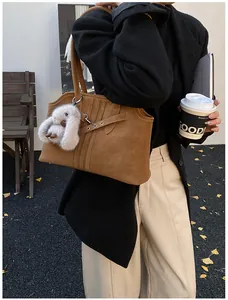 Détail d'un grand sac cabas marron texturé avec boucle décorative et porte-clés lapin