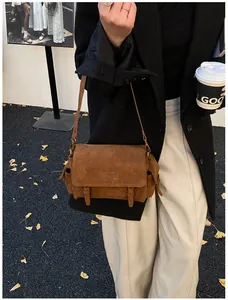 Outdoor shot of a vintage brown messenger bag with flap and dual buckle strap detail