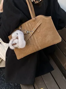 Sac cabas en daim marron rétro avec un lapin en peluche blanc sur un banc en bois