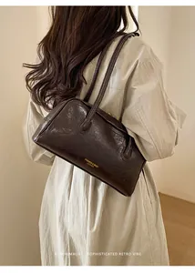 Detail of dark brown leather Boston bag with golden text logo on the side