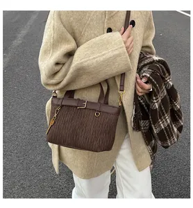 Detailed view of dark brown pleated bucket bag with vintage gold hardware and leather strap