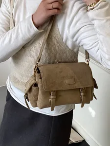Brown suede Boston bag with double buckles and side pockets shown on a shoulder