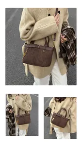 Detail of dark brown pleated bucket bag with gold hardware and key charm in autumn setting