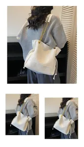 Close-up of geometric stitching and gold chain strap on a white leather bucket bag