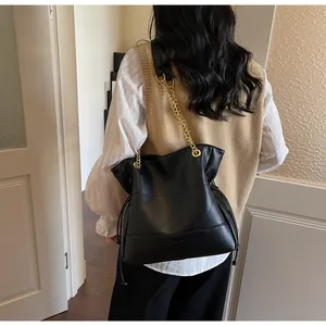 Detail of black tote bag with geometric stitching and gold chain shoulder strap
