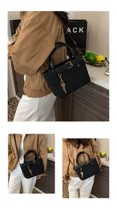 Detail view of black pleated bucket bag with gold square buckle and key pendant accessory