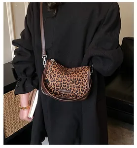 Detail of leopard print crossbody bag with star charm and long strap on model