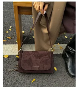 Nahaufnahme dunkelbraune Wildledertasche mit Goldschrift auf herbstlichem Hintergrund