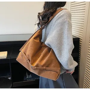 Dettaglio della borsa tote in pelle scamosciata marrone con fibbie laterali e texture morbida