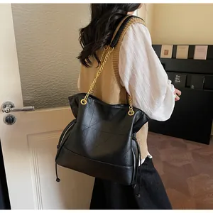 Detail of black tote bag featuring geometric stitching and gold chain leather strap