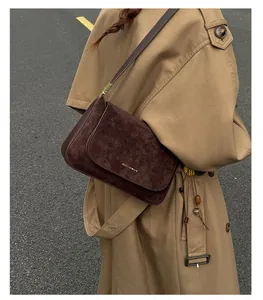 Detailansicht der dunkelbraunen Wildleder-Baguette-Tasche mit Goldlogo und Vintage-Klappe