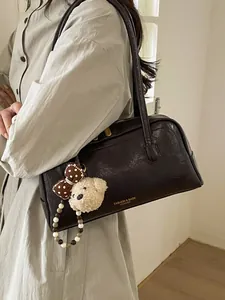 Retro dark brown leather Boston bag with plush charm shown on female model shoulder