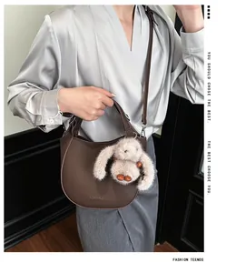 Detail view of dark brown pebbled leather bucket bag with cute plush rabbit charm