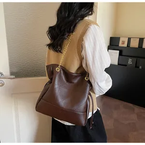 Close-up of brown quilted leather bucket bag with gold chain and drawstring detail