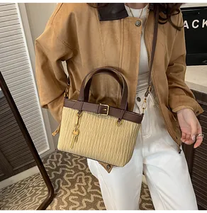 Detail of pleated bucket bag with brown straps and a golden key charm ornament