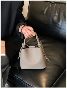 Dettaglio della borsa a secchiello in pelle taupe con trama e lacci laterali
