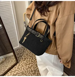 Close-up of black pleated bucket bag featuring golden buckle and metallic key charm