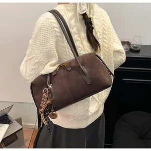 Détails de texture du sac Boston en daim marron avec pendentif chocolat et fermeture