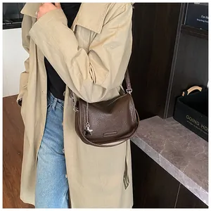 Detail of dark brown pebble leather shoulder bag with star charm and metal chain