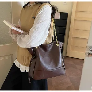 Detail of dark brown tote bag showing geometric stitching and golden chain strap