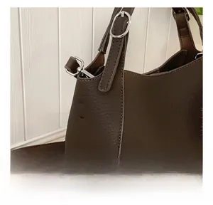 Close-up of litchi grain leather texture and precise stitching on dark brown bucket bag