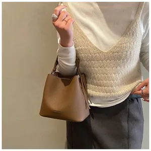 Dettaglio della texture in pelle a grana e del logo del marchio sulla borsa a secchiello