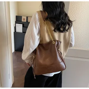 Detail of vintage brown leather bucket bag with geometric stitching and chain strap