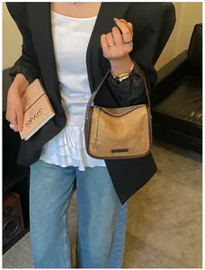Brown suede underarm bag with metal star charm shown in a professional lifestyle setting