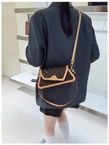 Detail showing the brown monogram crossbody bag worn over the shoulder by a model