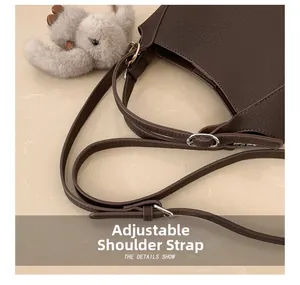 Detail view of the adjustable shoulder strap on a dark brown litchi grain leather bag