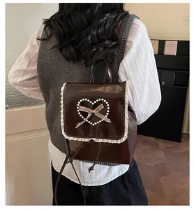 Detail view of coffee leather backpack featuring pearl heart and lace trim details