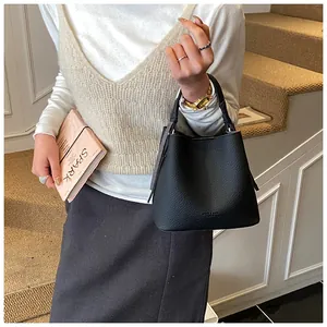 Dettaglio della borsa a secchiello in pelle nera martellata indossata da modella