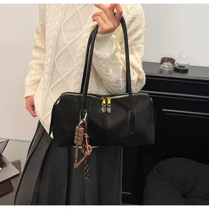 Détail d'un cabas noir mat avec zips dorés et pendentif chocolat décoratif