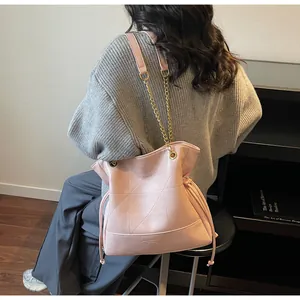 Detail view of pink bucket bag with geometric quilting and golden chain strap