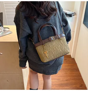 Detail of khaki pleated bucket bag with brown leather handle and gold key pendant charm