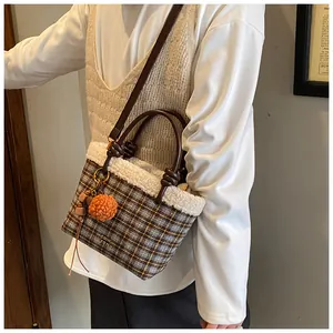 Détail du sac seau écossais avec bordure en fourrure, pompon orange et bandoulière fine