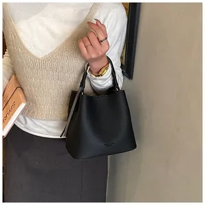 Dettaglio della borsa a secchiello nera con trama a grana fine e logo in rilievo
