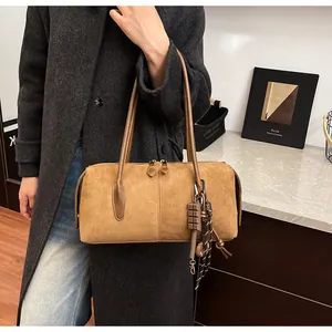 Détail du sac bowling en daim fauve avec charm chocolat et cordon bicolore tressé