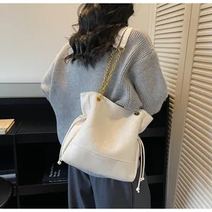 Detailed close-up of quilted white bucket bag with gold chain strap and drawstring closure