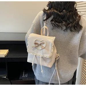 Detail of lace trim and pearl heart design on cream faux leather mini backpack