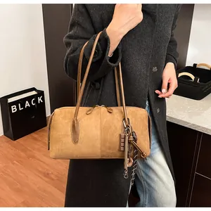 Détail d'un sac Boston vintage en cuir dépoli marron avec des charms créatifs et bandoulière
