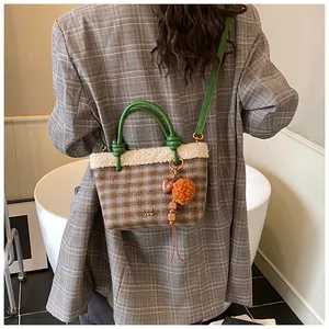Détail du sac seau à carreaux avec poignées en cuir vert et bordure en fourrure