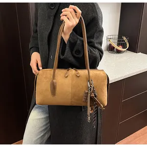 Sac cabas vintage en daim marron avec breloques porté sur un manteau en laine