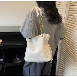 Detail view of the white bucket bag featuring geometric stitching and gold chain strap