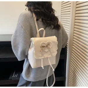 Detail view of cream backpack with lace trim, pearl heart and plaid bow accent