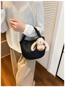 Detail of black crescent hobo bag with lychee texture and plush bunny charm
