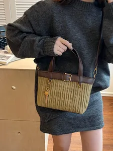 Minimalist matcha green pleated bucket bag with brown handles and a gold key pendant